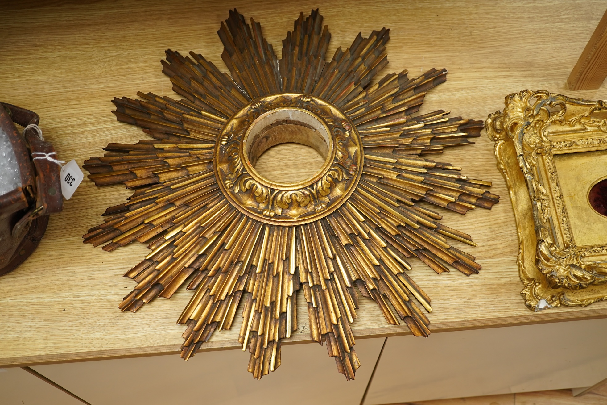 A gilt decorated sun burst clock frame, 63cm wide and a mid 19th century ornate gilt miniature frame